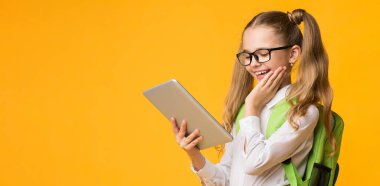 Dijital Tablet Eğitim Uygulaması Okul Ödevlerini Çevrimiçi Olarak Sarı Stüdyo Arkaplanı Üzerinde Kullanan Mutlu İlkokul Öğrencisi Kız. Boş Alan