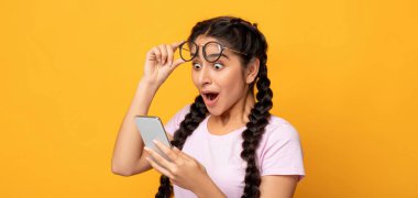 Harika haberlerim var. Heyecanlı Hintli Kadın Tutma ve Zeka Telefonu Kullanma, Sosyal Medya Bakımı Portresi. Duygusal Genç Bayan Başarılı Oluyor, Gözlüklerini Çıkartıyor, Sarı Stüdyo Geçmişi