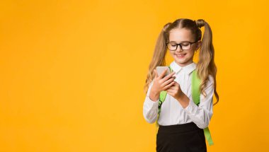 Eğitim Okulu Uygulaması. Smartphone kullanan liseli kız sarı arka planda duruyor. Metin için Boş Alan