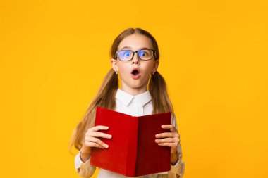 Okumayı öğrenmek. Sürpriz küçük okul öğrenci kız Sarı Stüdyo arka plan kitap ile poz. Boş Alan