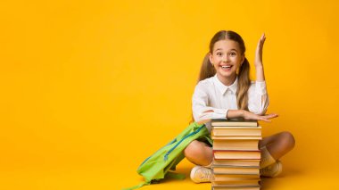 Düz bir öğrenci. Akıllı Schoolgirl Sarı Stüdyo Arka Plan Üzerinde Kitap Yığını Oturan El Raising. Metin için Boş Alan