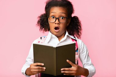 Şaşırmış liseli kız elinde kitapla arka planda şaşırtıcı pozlar veren kameraya bakıyor. Stüdyo Çekimi