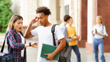 Acele et! Üniversite kampüsündeki çok ırklı öğrenciler saatlere bakıyor.
