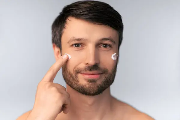 stock image Skincare. Middle Aged Man Applying Anti-Aging Cream On Face Skin Over White Background. Studio Shot, Isolated