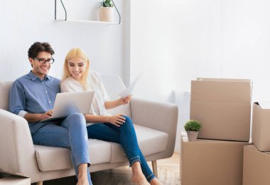 Neşeli Karı Koca Yeni Daire kanepede oturan Laptop Tarama. Kopyalama Alanı