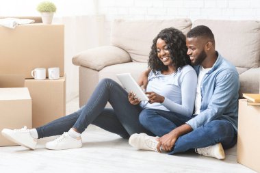 Yeni bir daire ayarlıyorum. Genç Afrikalı kadın, erkeğine dijital tablet ve boş alan kullanarak iç mekan hakkında fikir veriyor.