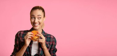 Hile Yemeği. Sarı Stüdyo Arkaplanı Üzerinde Güzel Bayan Hamburger Yiyen. Boş Alan