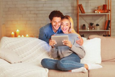 Olumlu çift dijital tablette haberleri okuyor evdeki koltukta dinleniyor. Seçici Odaklanma