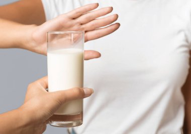 Gri arka planda stüdyoda duran bir bardak süte hayır diyen tanınmamış bir kadın. Kırpılmış, Seçici Odaklanma