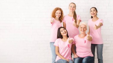 Pembe Meme Kanseri T-Shirt Kurdeleler Gesturing Thumbs-Up Beyaz Tuğla Duvar Üzerinde Poz ile Çeşitli Kadın Gönüllüler. Kopyalama Alanı