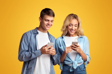 Meraklı erkek arkadaş, kız arkadaşlarını gözetliyor, akıllı telefon mesajlarını okumaya çalışıyor, sarı stüdyo arka planında fotokopi alanı var.