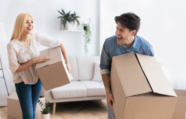 Genç bir çift yeni evlerinde büyük karton kutular taşıyor..