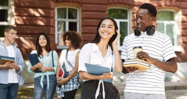 Üniversite zamanı. Kampüste tatilde dinlenen, kahve içip sohbet eden mutlu öğrenciler.