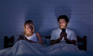 Sadakatsizlik Kavramı. Sadakatsiz Girlfriend Gece Yatakta Erkek Arkadaşı ile Yatarken Telefonda Sohbet. Düşük Işık, Seçici Odak