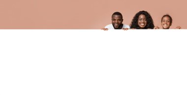 Aile teklifi. Siyah ebeveynler ve kızları reklam için boş beyaz tahtaya yaslanıyorlar.