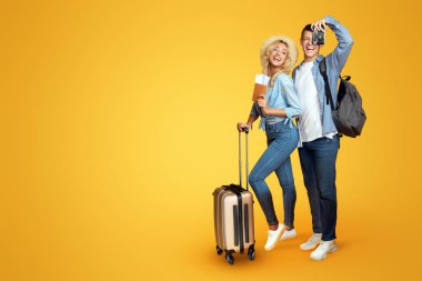 Tatile hazır. Sarı arka plan üzerinde bavul ve bilet ile Mutlu çift, kopya alanı