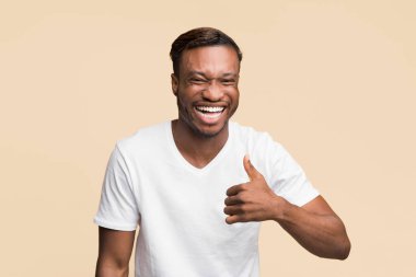 Gibi. Pozitif siyah adam gülüyor ve işaret ediyor. Sarı arka planda duran komik şakayı onaylıyor. Stüdyo Çekimi