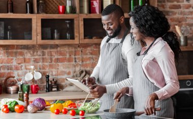 Vejetaryen yemek pişirirken dijital tablet kullanarak Lovely Afrikalı çift, kopya alanı