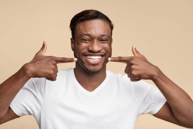 Gülümseme. Mutlu Siyah Adam Sarı Stüdyo arka plan üzerinde duran onun beyaz dişleri parmaklarını işaret