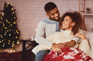 Sıcak kış tatili. Sevgili çift Noel arifesinin tadını çıkarıyor, kanepede ekoseyle kaplanmış.