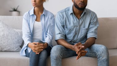 Eşler arasındaki yanlış anlaşılma. Afro çift, danışmanlık ofisindeki koltukta otururken göz temasından kaçınıyor.