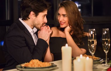 Yakışıklı adam el onun kız arkadaşı restoranda romantik bir akşam yemeği sırasında öpüşme