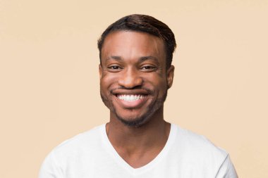 Beyaz tişörtlü neşeli siyahi adamın portresi. Sarı arka planda kameraya gülümsüyor. Stüdyo Çekimi