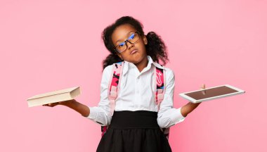 Gadgets Kitaplara Karşı. Afro İlköğretim Okulu Kızı Tablet ve Kitabı Sarı Arkaplanda Karşılaştırıyor. Stüdyo Çekimi