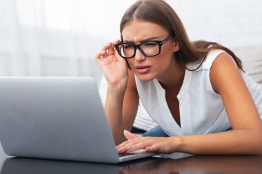 Görme. Genç Kadın Laptop At Gözlük bakarak Yakın Vizyon Sorunu Kanepede Kapalı Oturan sahip. Seçici Odak