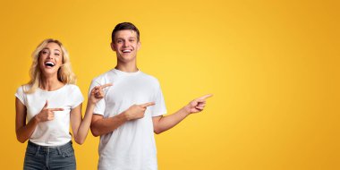 Neşeli genç adam ve kız uzak sarı arka plan üzerinde kopya alanı işaret