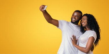 Gülümseyen Afro-Amerikan Çift Selfie Alıyor, sarı stüdyo arka plan, kopya alanı