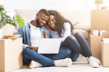 Afrikalı aşıklar yeni bir daireye taşınıyor, dizüstü bilgisayar kullanarak iç dizaynı seçiyorlar.