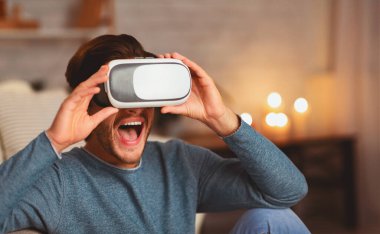 Video kayıt cihazı. Sanal gerçeklik gözlüğü takan heyecanlı adam akşamları evde eğleniyor. Seçici Odaklanma