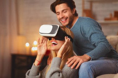 Video kayıt cihazı. Mutlu çift, akşam evde evde buluşurken sanal gerçekliği tecrübe ederken eğleniyor.