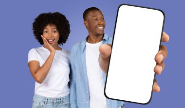 Afrikalı Amerikalı genç bir kadın, elinde boş ekranla telefonu tutan bir adam görünce şaşırmış görünüyor. Arkaplan koyu mavi renkte..