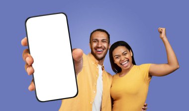 Siyah adam ve kadın kameraya gülümsüyor ve boş bir ekranla akıllı telefonu tutarken bakıyorlar. Adam telefonu önünde tutuyor, kadın da sağ kolunu kaldırıyor.