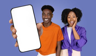 Afro-Amerikalı kadın ve erkek mavi bir arka planın önünde yan yana duruyorlar. Adam ekranı boş olan akıllı bir telefonu izleyiciye doğru tutuyor.