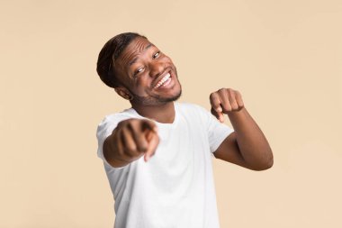 Hey, sen. Sarı Stüdyo Arkaplanı 'nın üzerinde duran kamerayı işaret eden gülümseyen siyah adam. Seçici Odaklanma