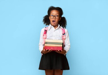 Küçük liseli kızın elinde okul kitaplarıyla kameraya bakarken sarı arka planda ağzı açık poz vermesine şaşırdım. Stüdyo Çekimi