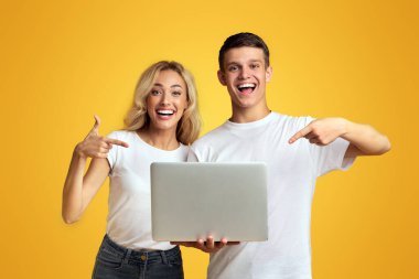 Serin web sitesi. Mutlu gençler dizüstü bilgisayar tutan ve sarı arka plan üzerinde işaret, kopya alanı