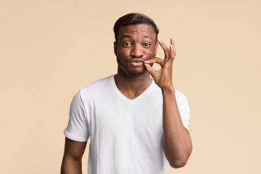 Tek kelime etme. Sarı Arkaplan 'ın üzerinde duran Afro Adam Dudağının Fermuarını Çekiyor. Stüdyo Çekimi