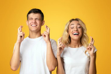Değerli dilekler. Genç adam ve kadın kapalı gözleri ile umut ile parmakları geçiş, kopya alanı ile sarı arka plan