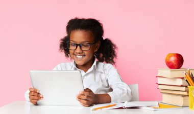 Gülümseyen Afro Öğrenci Kız Tablet Bilgisayar kullanarak Sarı Stüdyo Arkaplanının üzerinde oturuyor. Okul ve Gadget Kavramı.