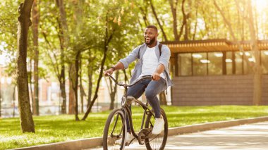 İlk tur. Parkta bisiklet süren, işe giden, sırt çantalı heyecanlı siyah adam.