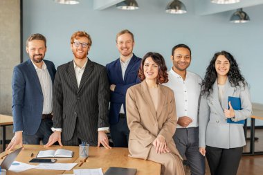 Modern bir ofis ortamında bir grup iş adamı bir arada duruyor. Hepsi kendinden emin, başarılı, şık giyinmiş ve kameraya içten bir şekilde gülümsüyor.