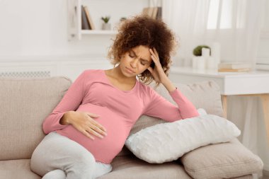 Hamilelik sırasında hastalık. Genç hamile kadın koltukta acı çektiği için kötü hissediyor.