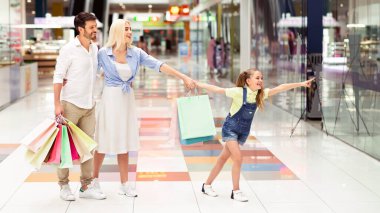 Alışveriş merkezinde aile alışverişi. Küçük Kız İşaret Parmak Hipermarket yürüyüş ailesine mağaza penceresinde bir şey gösteren.