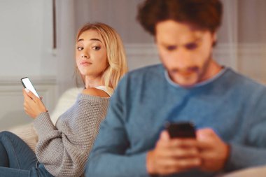 Hile İşaretleri. Erkek arkadaşına telefonla mesaj atıp sadakatsizlikşüphesi yla bakıyor evde kanepede oturuyor. Seçici Odak