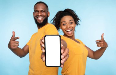 Bu yeni uygulamayı kullan. Neşeli siyah çift boş ekranlı akıllı telefonu işaret ediyor, mobil uygulama öneriyorlar, web sitenizi tanıtıyorlar, tasarım için modelleme yapıyorlar. Seçici odak