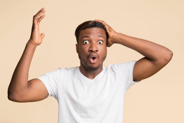 Tüh. Kafasını tutup, sarı arka planda duran kameraya bakarak hareket eden afro-amerikalı adam şok oldu..